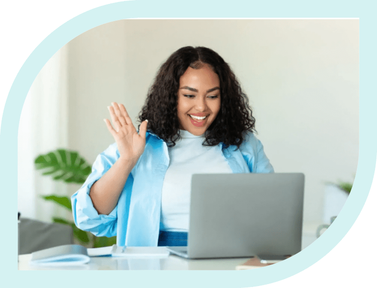 Smiling woman waving at her laptop during a video call.