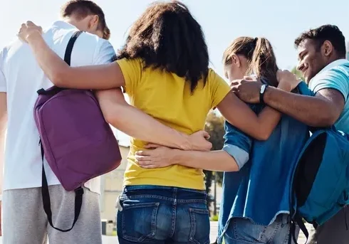 Group of friends standing closely with arms around each other outdoors.